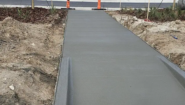 Handicap freshly poured concrete sidewalk ramp leading to a street, designed for accessibility compliance.
